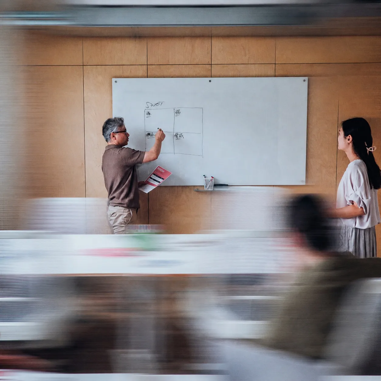 Two colleagues working through a plan on a whiteboard